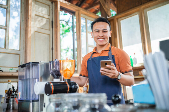 coffee shop waiter standing holding phone with smiling face