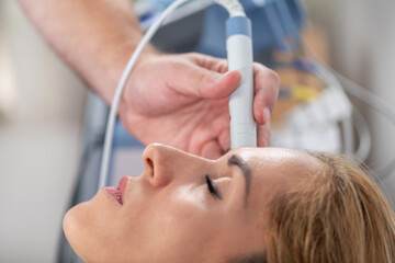 A physical therapist performs laser therapy on a patients sinus area to relieve sinus pain and reduce inflammation. This non-invasive treatment aims to promote sinus drainage and comfort