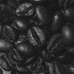 A high-contrast black and white close-up photograph of coffee beans, highlighting their texture and natural details. The monochrome palette adds depth and drama, making this image perfect for themes o
