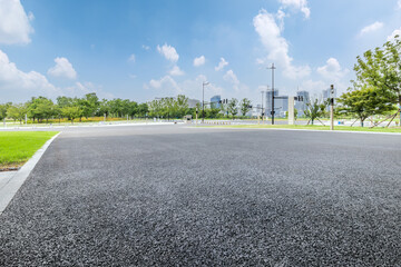 Empty asphalt road with woods and city buildings under construction in the distance