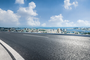 Fototapeta premium Empty asphalt road and city skyline with mountains landscape