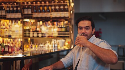 Smiling smart man drinking cocktail in Old fashioned with enjoy dancing in cheers with friends or stranger special vibrant beverage at nightclub on Friday meeting at luxurious counter bar. Vinosity.