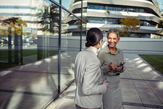 Professional women discussing something on a phone in a modern office building - Powered by Adobe