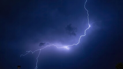 Lightning strikes dramatically during a nighttime storm over a darkened landscape