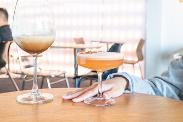 Glass of Cold Orange Mocktail on table,female hand swirling red wine in wine glass,Friends cheering with wineglasses.