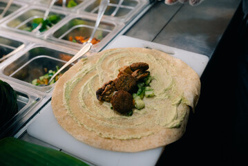 Chef making pita bread for falafel roll outdoor on street stall