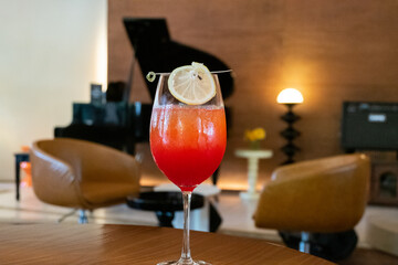 Premium Alcoholic Cocktail with blurred music band as background,Pleasant Evening In Respectable Restaurant With Cocktail,close up of wine glass on wooden table with blurry bar background scene.