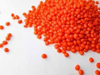 Orange taffy masterbatch granules on white background,color pigment carrier polymer in plastic industry,suitable for plastic company catalogue