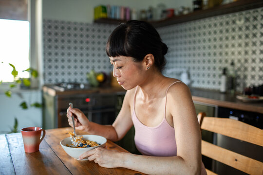 Woman eating healthy breakfast in kitchen at home
