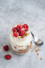 Greek yogurt parfait with granola and fresh berries in a jar on grey background. Healthy vegetarian snack or breakfast meal