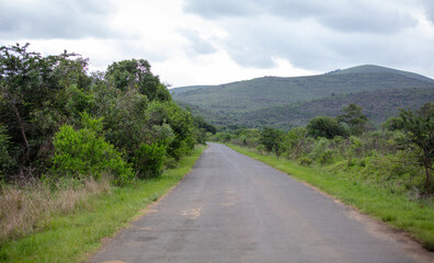 Highway in South African countryside. Grassy fields and farmland, blue sky with fluffy clouds