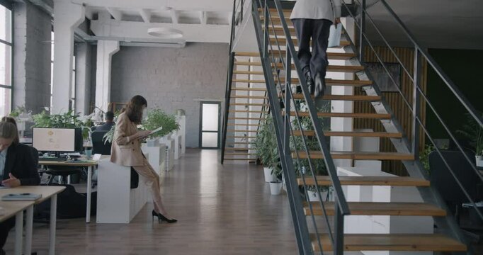 Businesspeople diverse group working in office walking talking using computers at desks. Busy workplace and professional occupation concept.