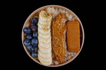 Perfect breakfast with whole oat, oat milk, chia seeds, banana, fresh blueberries, natural peanut butter and honey on black background
