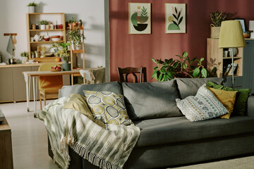 Cozy living room setting featuring a comfortable sofa with patterned cushions, surrounded by green...