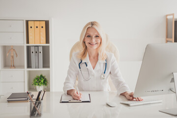 Confident mature female doctor in hospital office ready to consult and provide healthcare services