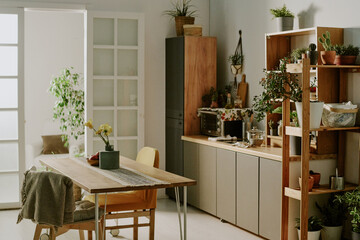 Bright and cozy kitchen featuring wooden furniture and various green plants. Shelving units and...