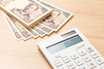 テーブルに置かれた106万円と電卓