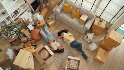 Top down aerial view of couple lesbian lying down at living room floor surrounded with cardboard box while sharing story in book. Happy lover spending time together and laughing together. Myrmidon. © InfiniteFlow