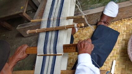 Blue and white scarf being woven on a backstrap loom in Carabuela, Ecuador