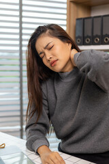 A female employee is suffering from office syndrome and is stretching to relax while working
