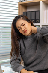 A female employee is suffering from office syndrome and is stretching to relax while working