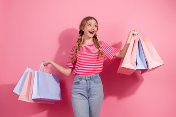 Charming young woman with braided hair holding colorful shopping bags in casual summer outfit on...