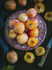 Home grown yellow and pink plums in a plate, top down view