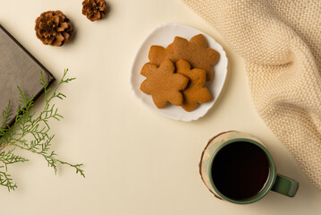 Winter coziness composition with cup of tea, gingerbread and book on beige background. Flat lay, top view.
