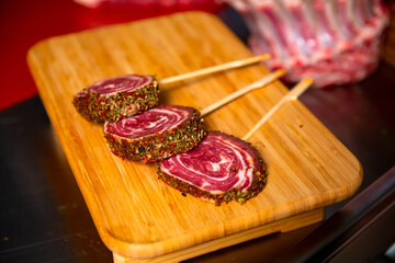 Rounds of fresh beef roulade seasoned with herbs on a wooden table in a butcher shop. Barbecue preps seasoned with pepper mix. Cooking conept.