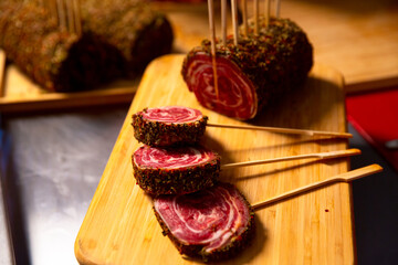 Meat roulade cuts with skewers on a wooden cutting board. Barbecue preps seasoned with pepper mix. Cooking conept.