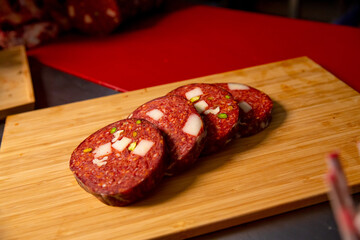 Four slices of meat sausage on the table. Pieces of scliced sausage on a wooden cutiing board.