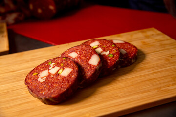 Four slices of meat sausage on a wooden table in a butcher shop. Pieces of scliced sausage on a wooden cutiing board.