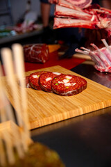 Slices of homemade sausageon with bacon and pistachios on wooden table in a butcher shop along with beef. Butchers table with sausage and ribs.