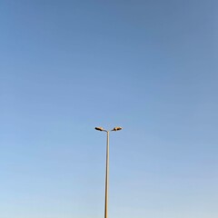 A minimalist view of a lamppost and a clear blue sky.
