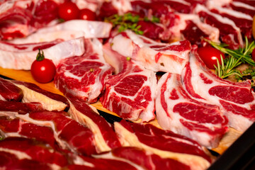Close-up Lamb ribs steak surrounded by diffferent meat handmade products. Shot of butchery manufactory table with meat goods.