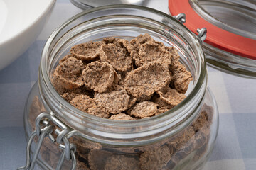 Glass bowl with dried brown buckwheat flakes for breakfast close up 