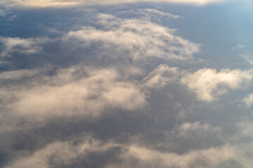 View of soft clouds under a vast sky during daytime flight above the landscape, capturing a serene atmosphere and natural beauty