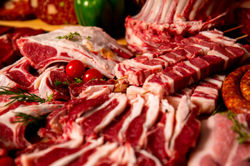 Fresh raw lamb carcass ready for sale on display on a wooden table with other meat products. Displayed raw lamb body for sale.