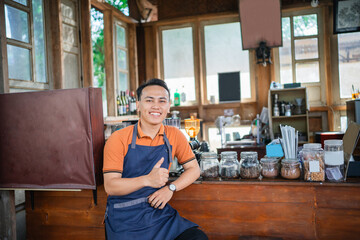 asian male barista working in a coffee shop, thumb up hand gesture