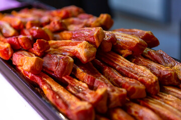 Smoked pork meat on tray for display cabinet at shop. Shop layout done in meat department. Food manufacture content.