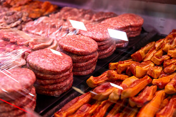 Raw minced meat beef burger cutlets in a window shop. Beef burgers and other meat preps ready to be sold. Food industry.