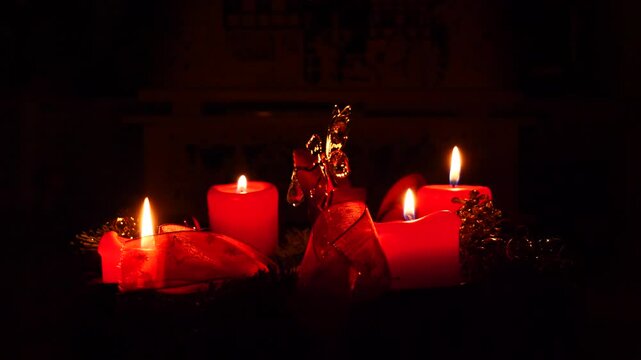 Ein goldener Engel dreht sich in einem Adventskranz zur Musik, vier rote Kerzen brennen zur Weihnachtszeit