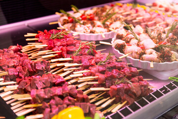 Beef meat and chicken rolls seasoned with mixed peppers and rosemery on skewers. Diverse raw meat products for sale.