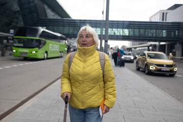 Senior female tourist in airport hold suitcase valise passport ticket schedule to check flight departure gate. Travel and tourism concept, people with backpack on shoulders. High quality photo