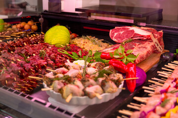 Grilled raw meat products seasoned with mixed peppers and rosemery on skewers. Diverse raw meat products for sale.