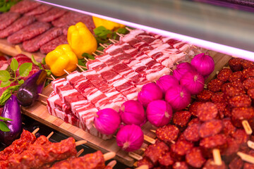 Grilled raw pork meat products seasoned with mixed peppers and rosemery on skewers. Diverse raw meat products for sale.