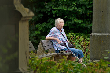 seniorin sitzt auf einer friedhofsbank