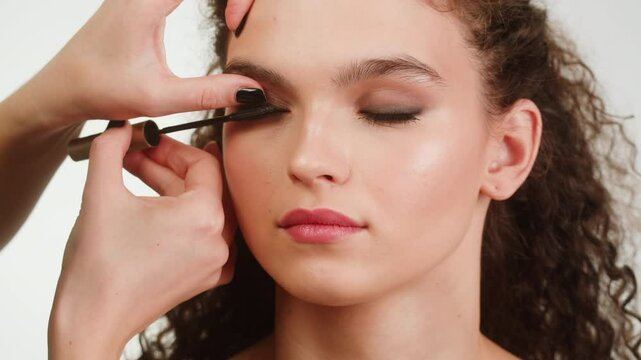 Closeup shot, style artist applies black mascara on the eyelashes of the female eye. Woman making make up using mascara. Professional makeup. Making mua. Smoky eyes makeup