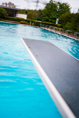 Inviting Diving Board Overlooking a Empty Tranquil Blue Outdoor Swimming Pool