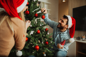 Man and woman decorating Christmas tree at home